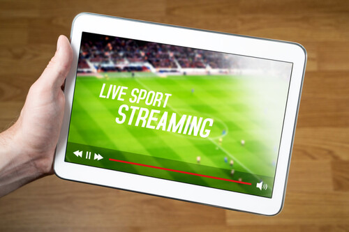 Man holding tablet streaming live sports.